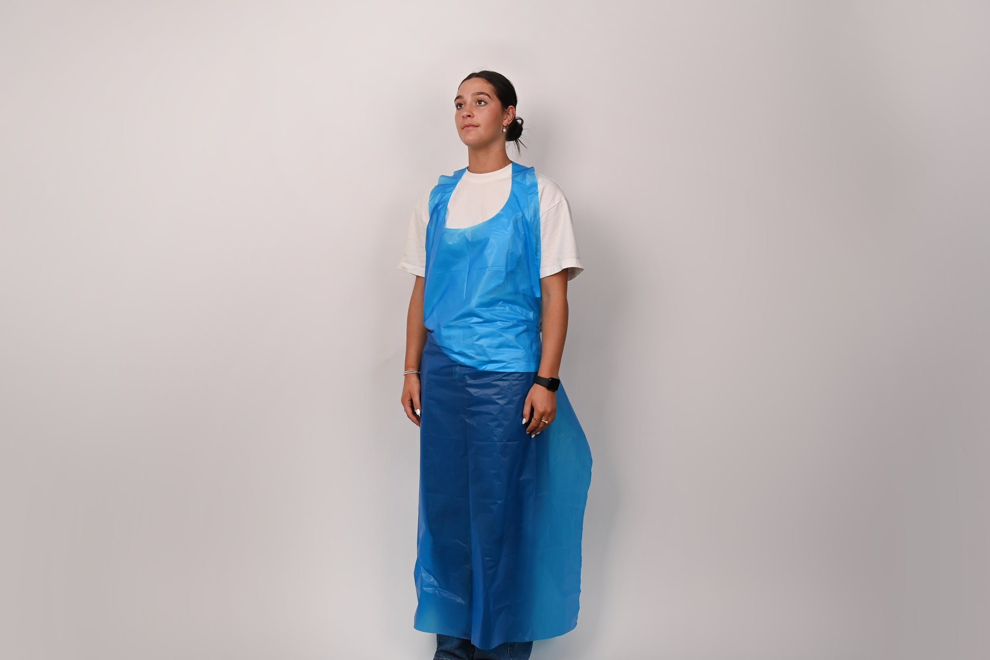 Person wearing a blue apron over a white shirt on a plain background