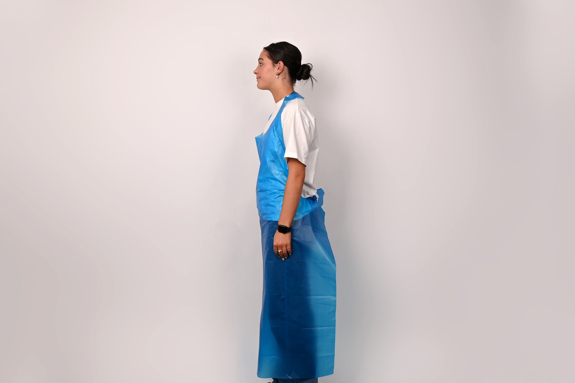 Person wearing a blue apron over a white shirt on a plain background