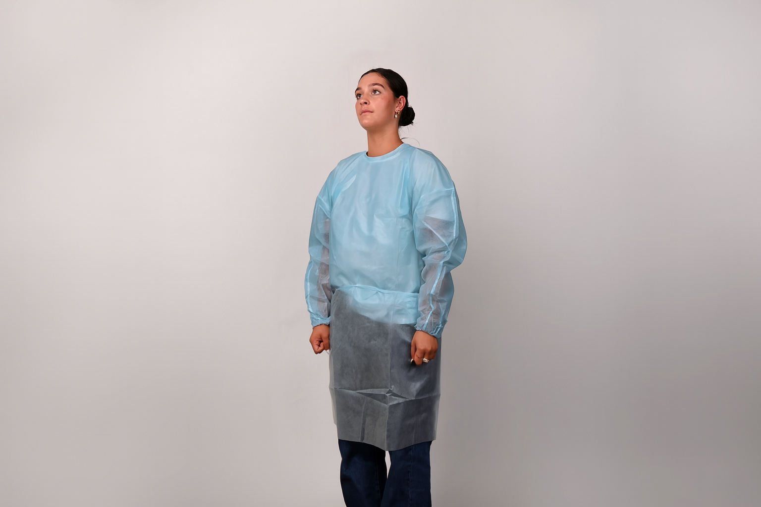 Person wearing a blue isolation gown on a grey background