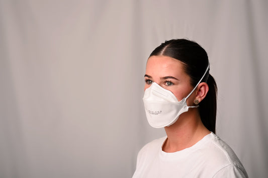 Person wearing a white P2 mask against a plain background