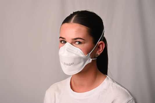 Person wearing a white N95 mask against a plain background