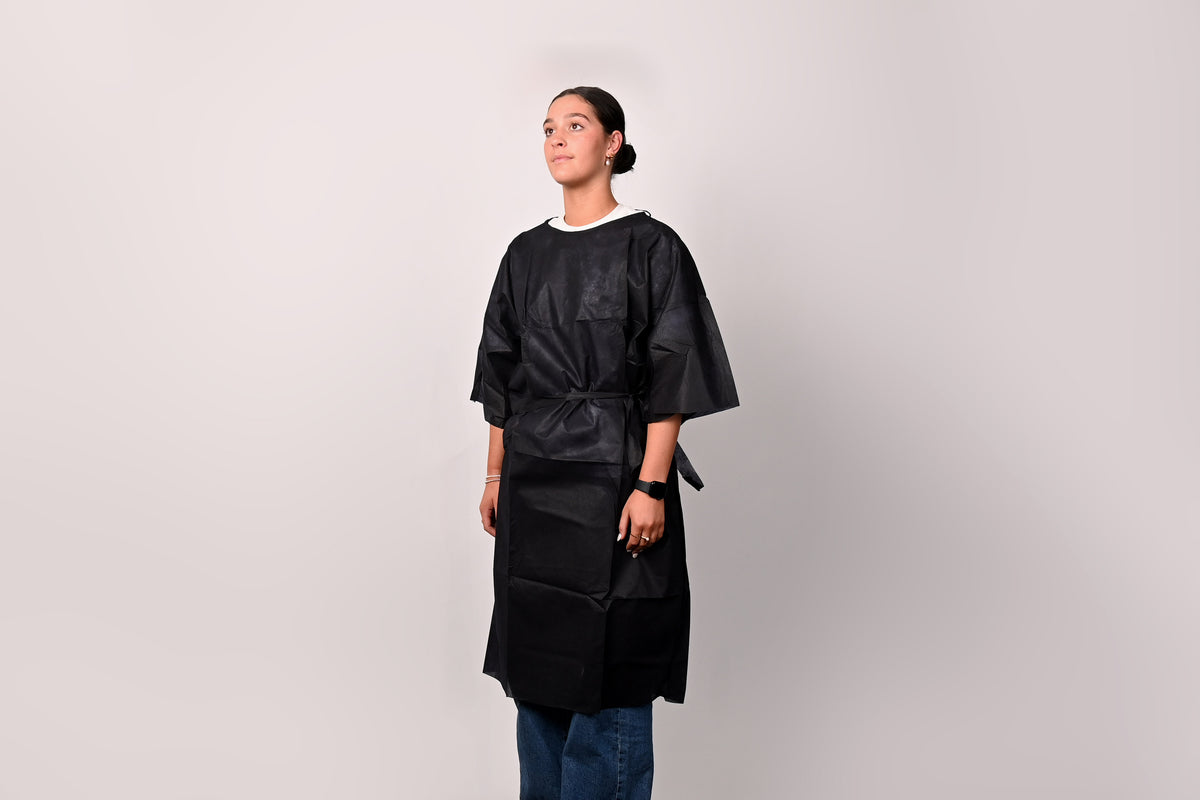 Person wearing a dark blue patient gown against a plain background