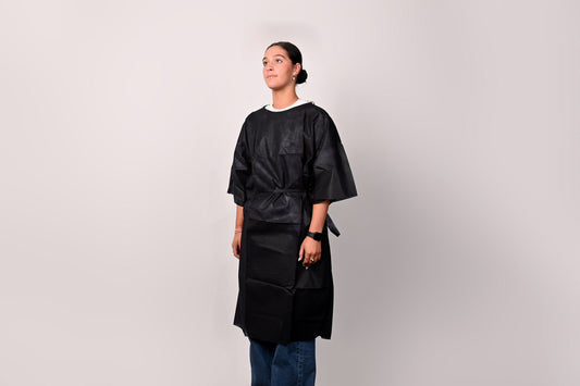 Person wearing a dark blue patient gown against a plain background