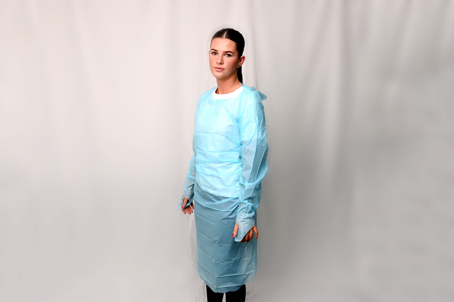 Person wearing a blue disposable gown against a plain background