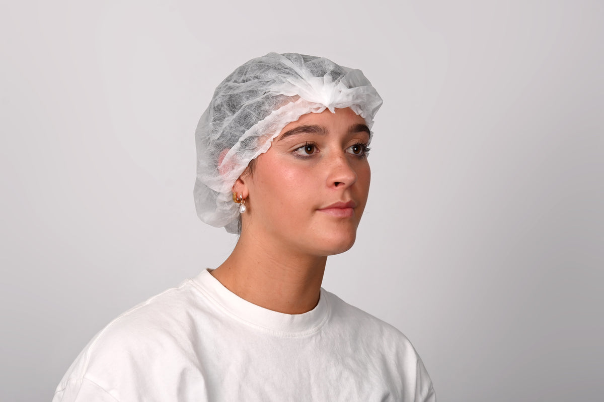 Person wearing a white hairnet and white shirt against a plain background