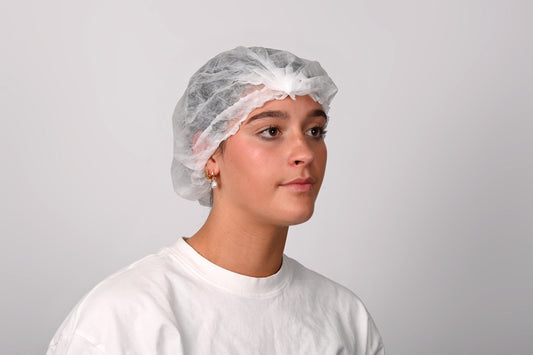 Person wearing a white hairnet and white shirt against a plain background