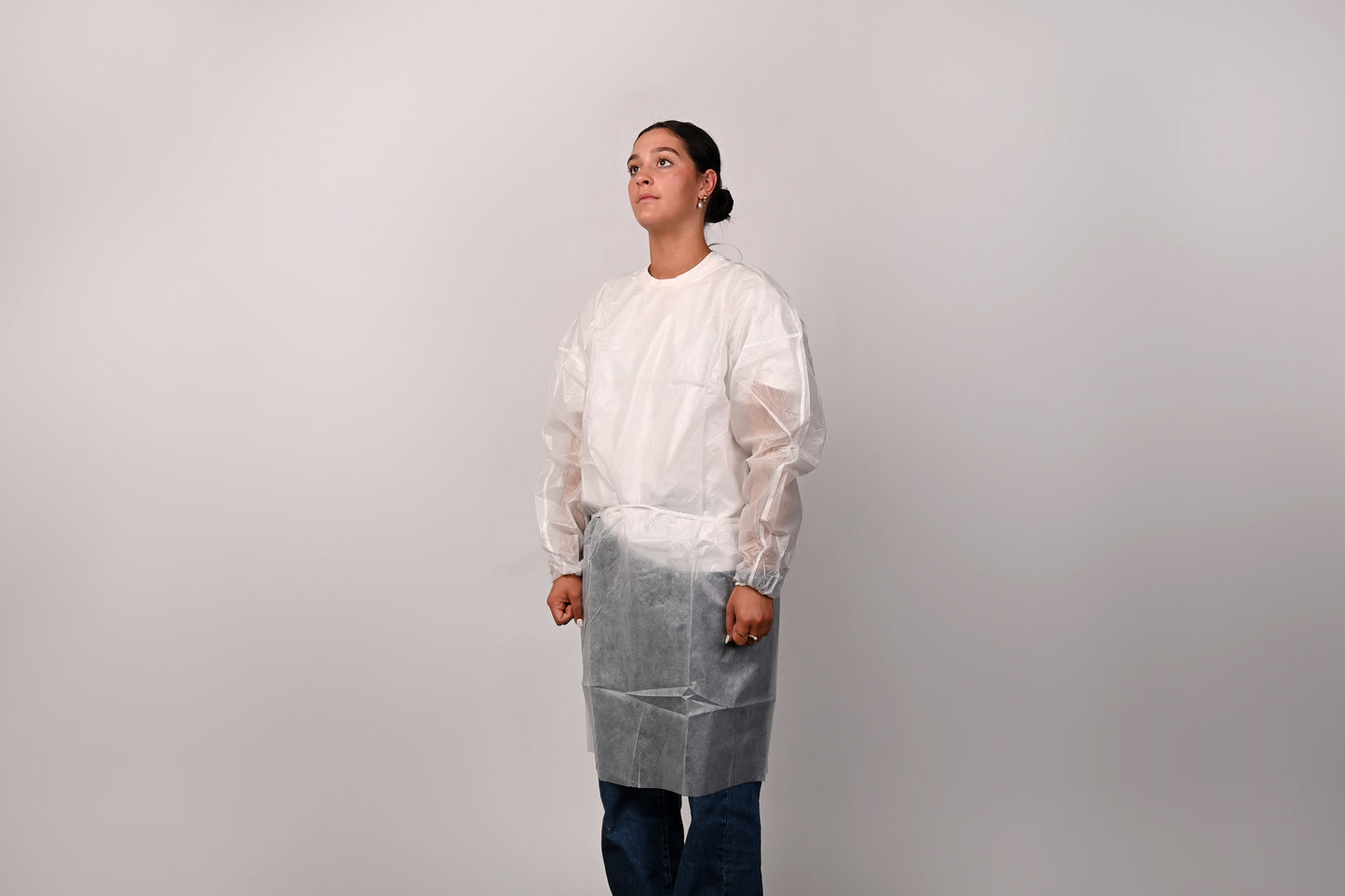 Person wearing a white isolation gown on a plain background