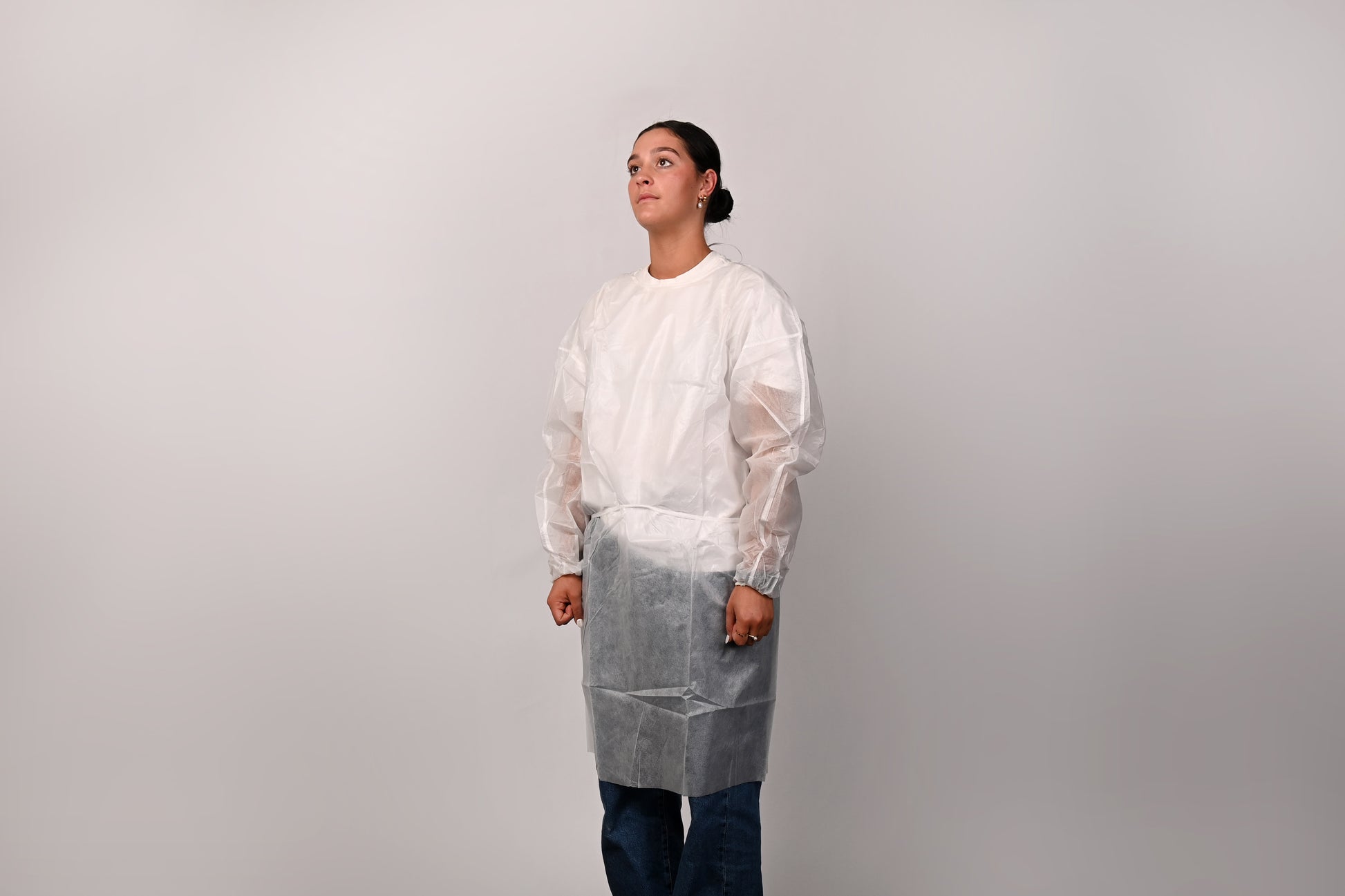 Person wearing a white isolation gown on a plain background
