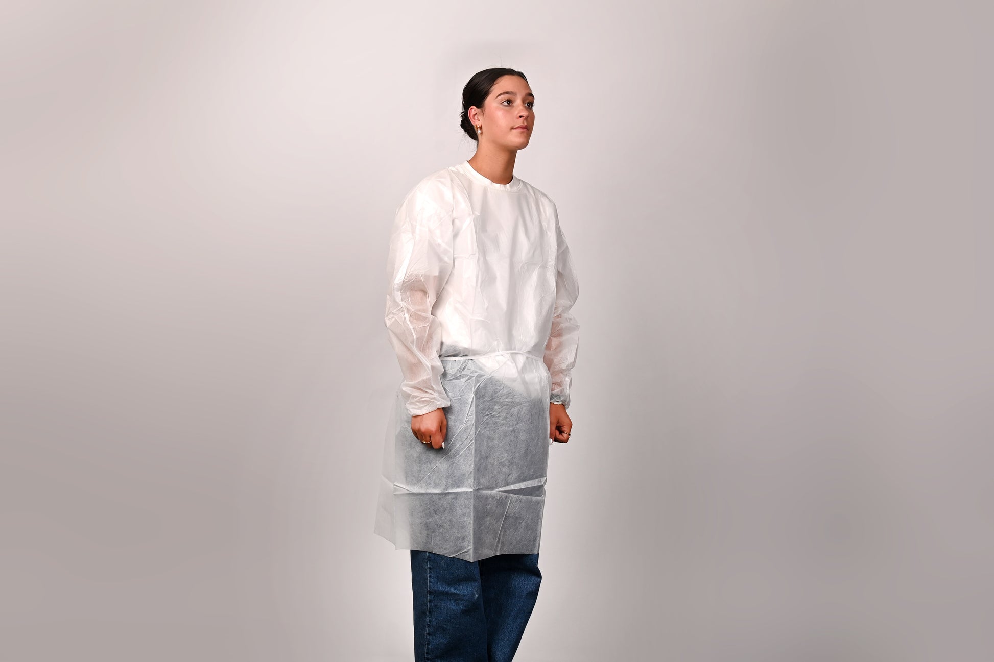 Person wearing a white isolation gown on a plain background